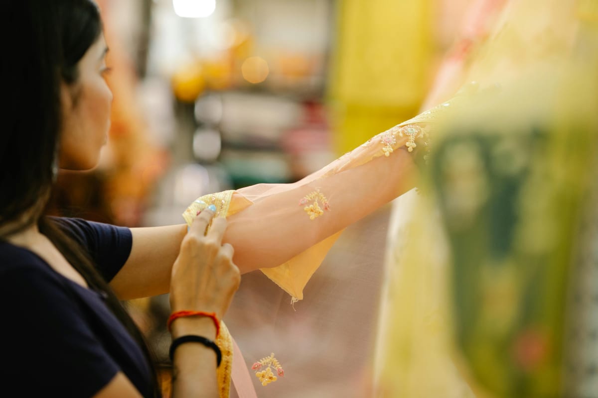 Close-up of a woman examining yellow embroidered fabric in a store.