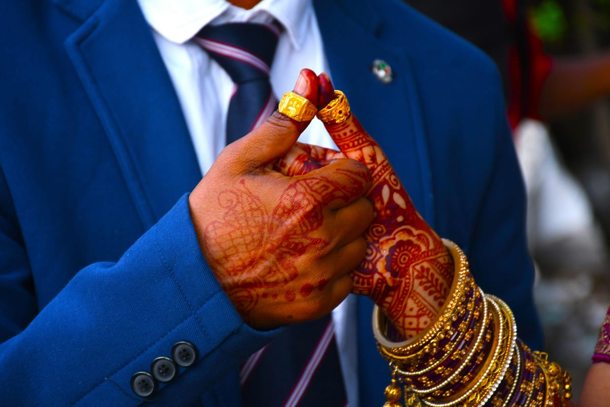 Close-up of an Indian wedding couple's hands with traditional mehndi and jewelry.