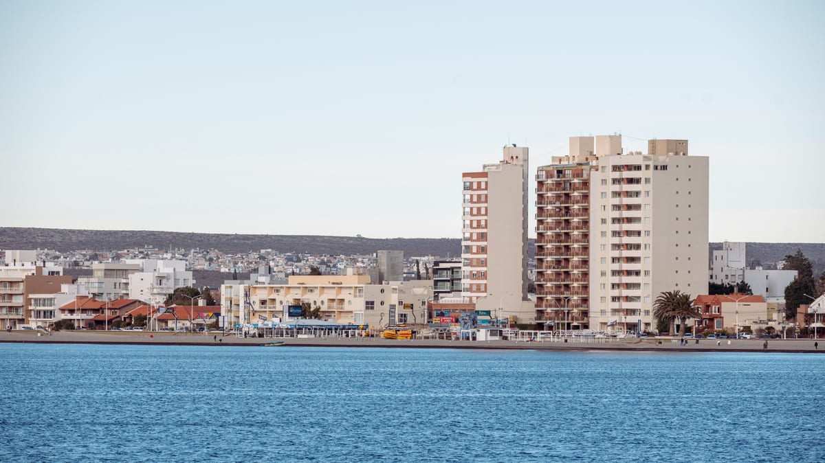A modern coastal cityscape with tall buildings along a waterfront, showcasing urban development.