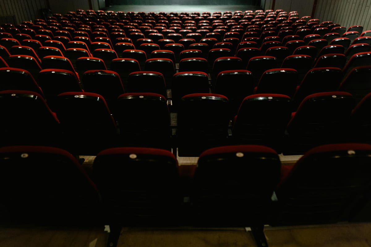 An empty movie theater interior with rows of red and black seats, awaiting audience.