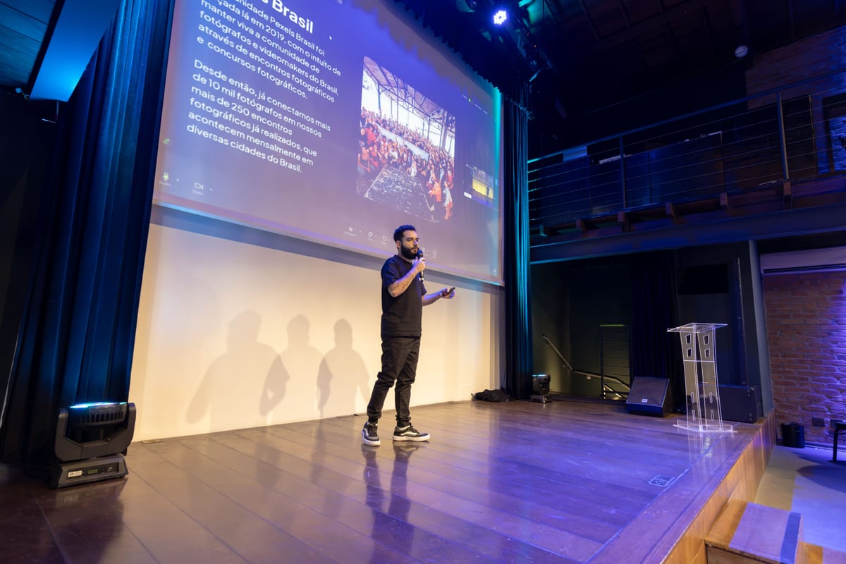 Speaker presenting at a conference with a projected presentation slide on screen.