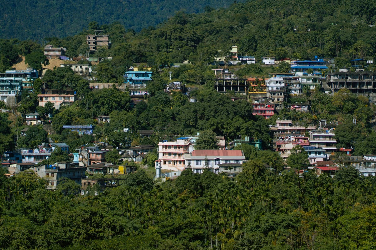 A vibrant hillside town with colorful buildings surrounded by lush greenery, showcasing a serene rural landscape.