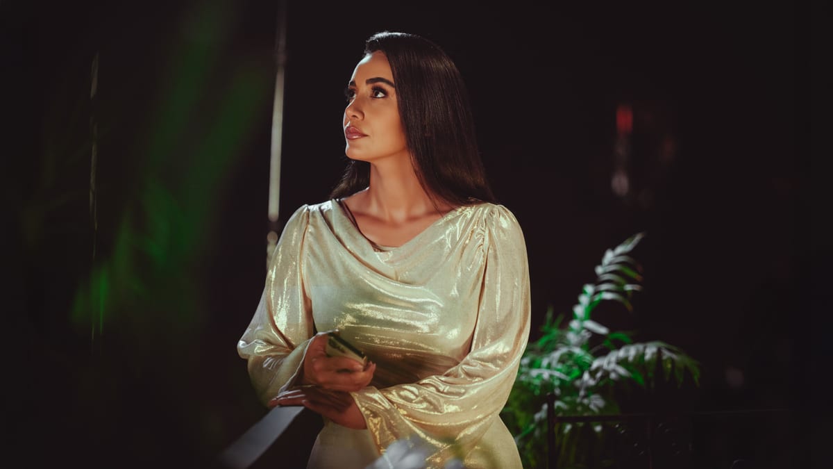 Woman in a shimmery gold dress under evening lights in Baghdad, Iraq.