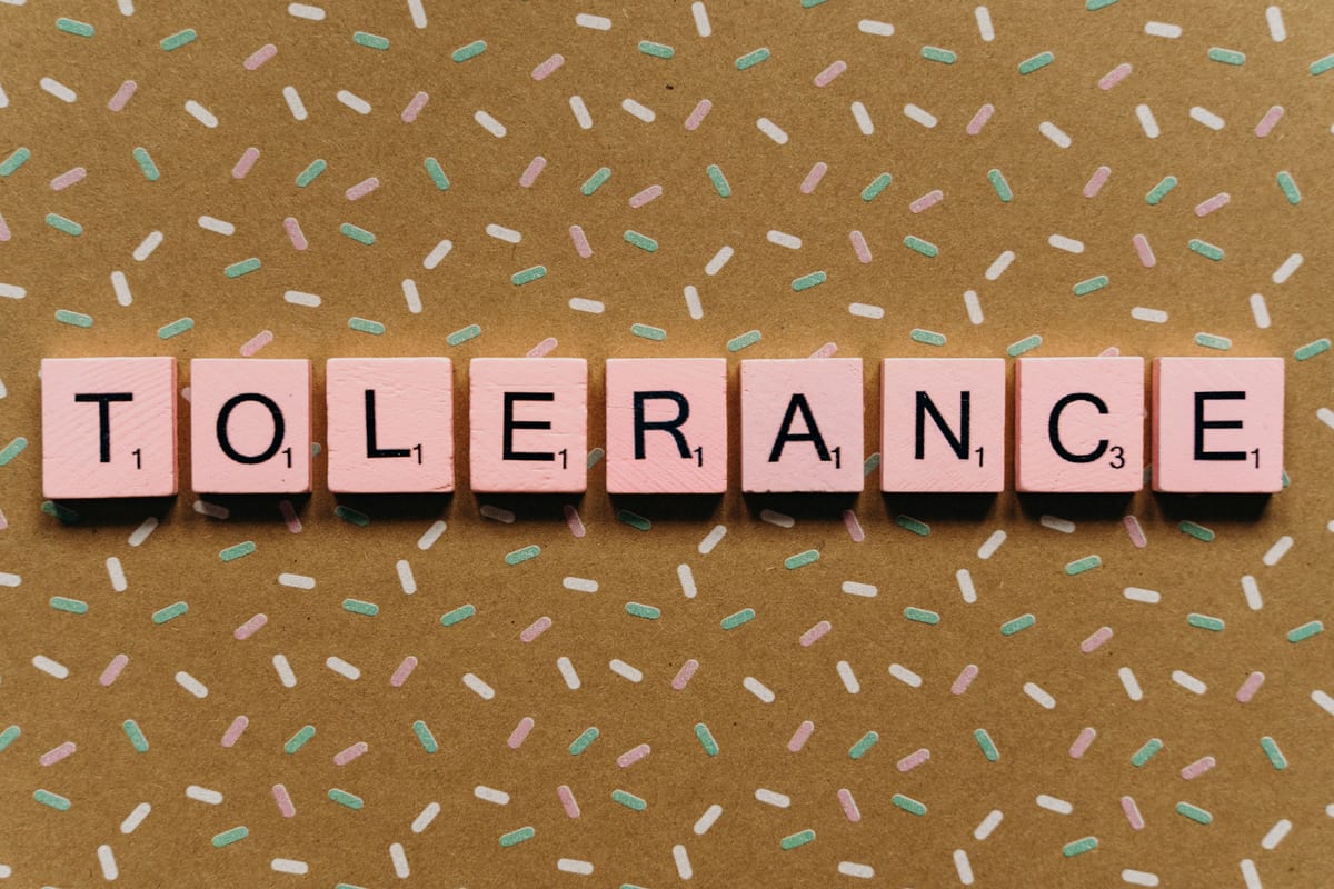 Scrabble tiles spelling 'TOLERANCE' on a patterned background promoting inclusivity.