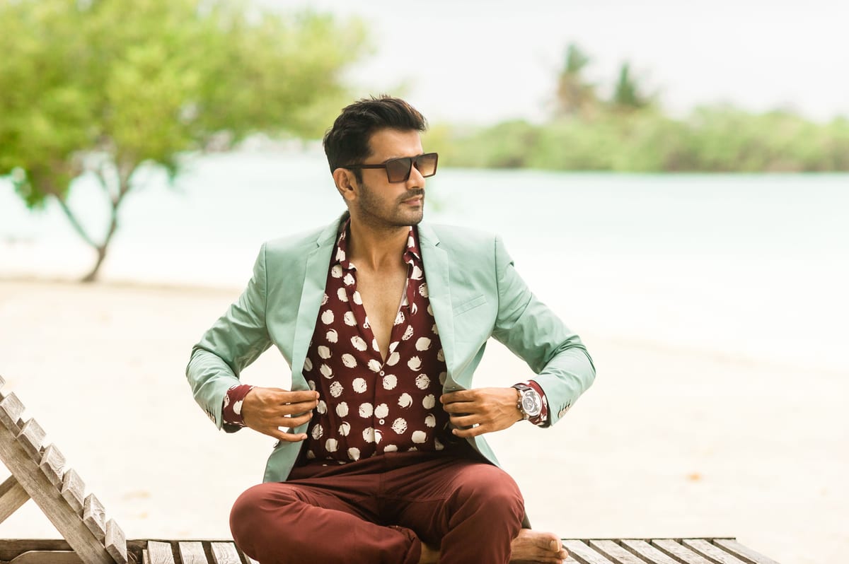 Fashionable man in designer attire enjoying a tropical beach view in the Maldives.