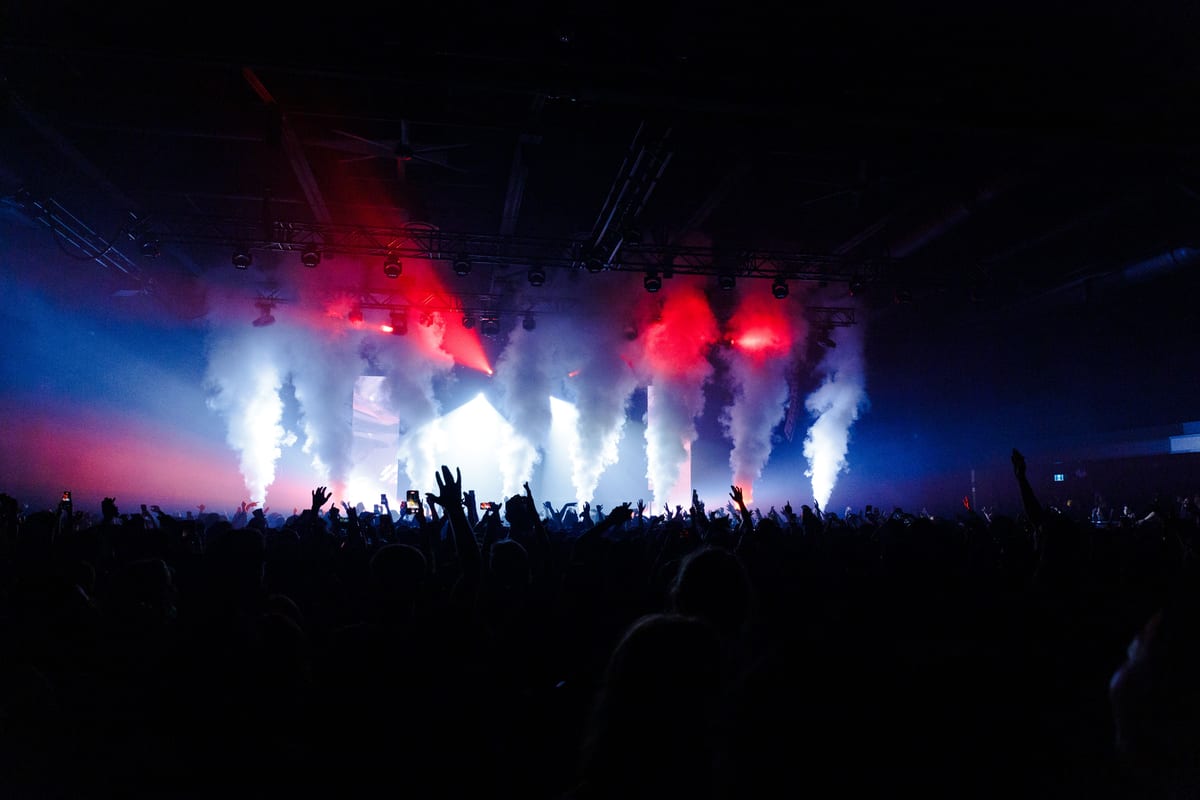 Energetic crowd at a concert enjoying dynamic smoke and lights.