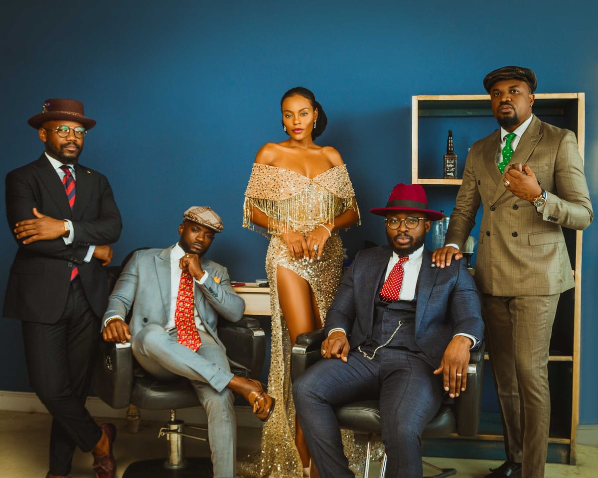 Group of fashionable people posing in suits and elegant dress against a blue background.