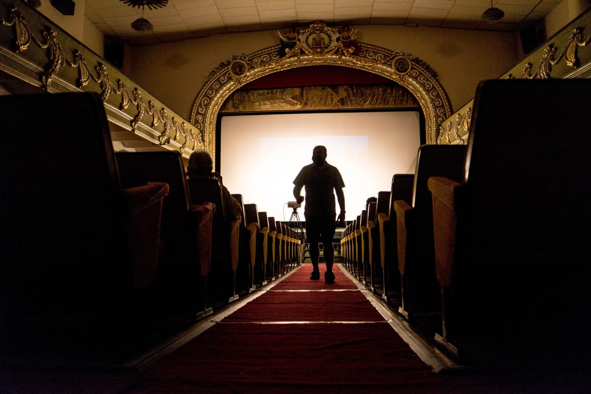 A person walking down an aisle in a vintage theater, showcasing ornate decor.