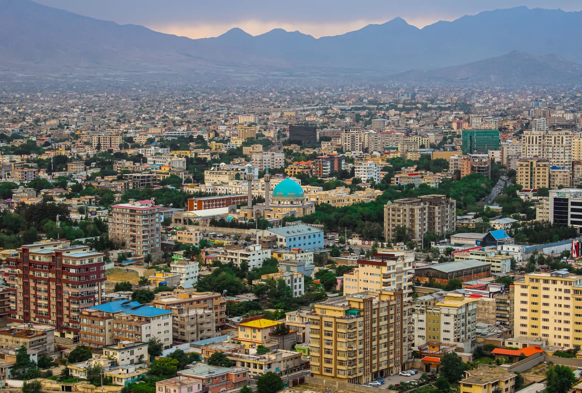 Aerial cityscape of Kabul featuring a prominent mosque amidst modern architecture and mountains.