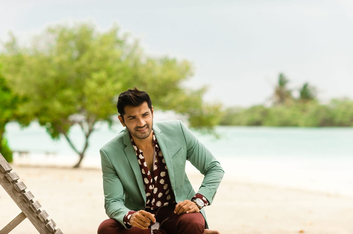 Fashionable man posing at a scenic Maldives beach resort in designer wear.
