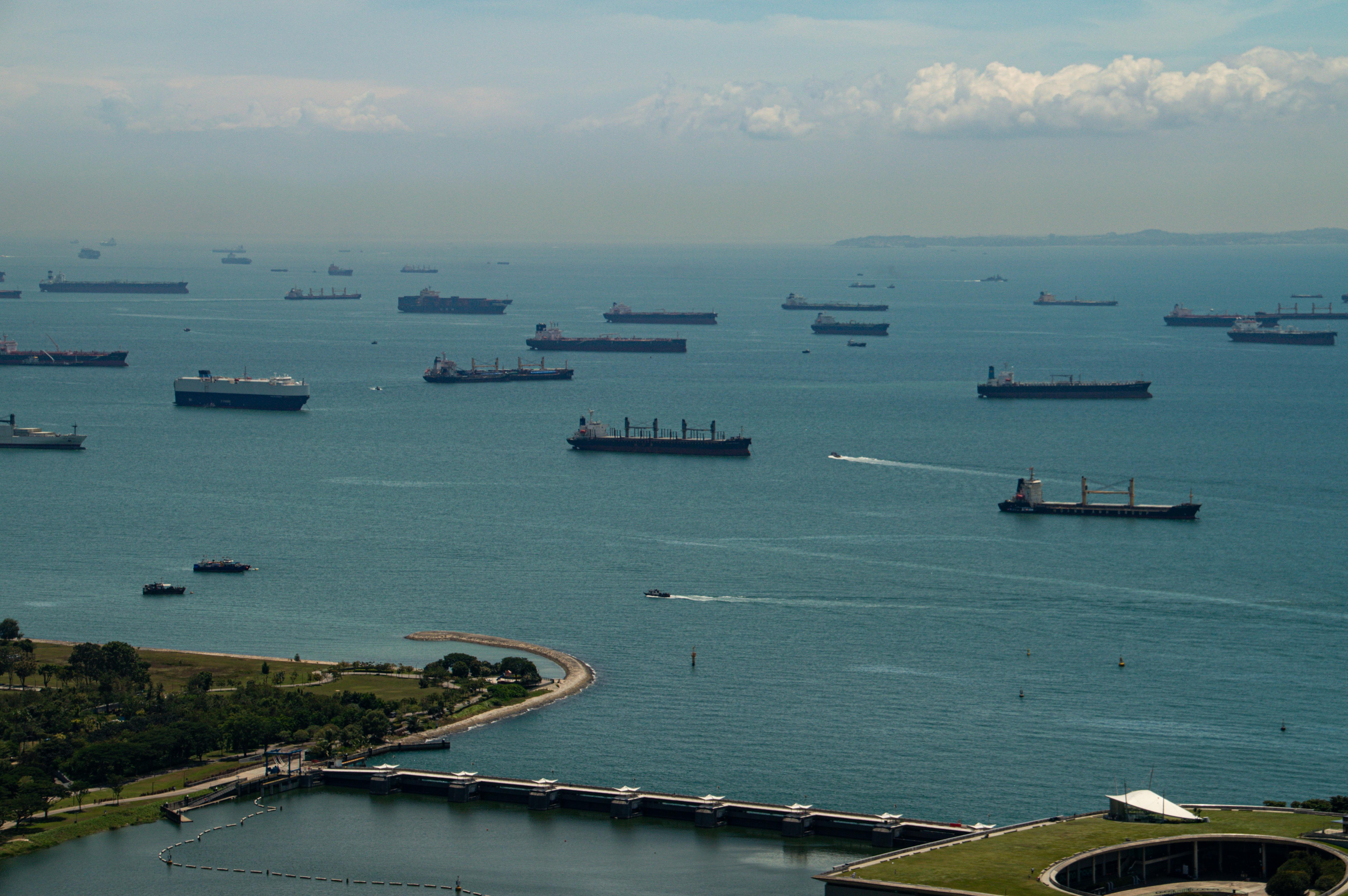 Aerial view of ships anchored in the Singapore Strait under a clear sky, showcasing maritime activity.