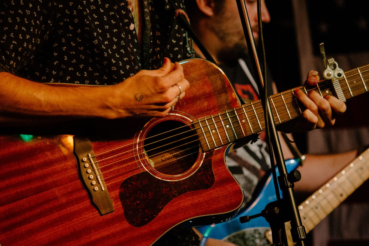 Hands playing an acoustic guitar during a live music performance in Boston.
